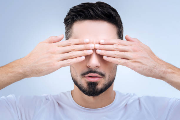 Shy person closing his eyes with two hands and rejecting any communication