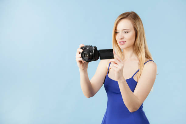 istock Blonde woman with camera on blue 874431608