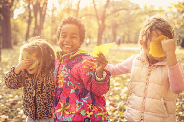 Little girls playing with fallen leaves.