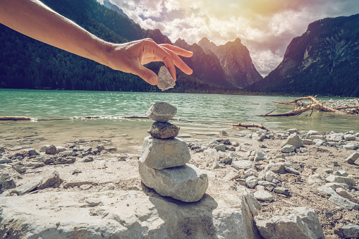 Detail of person stacking rocks by the lake, shot in Alto Adige, Italy.
