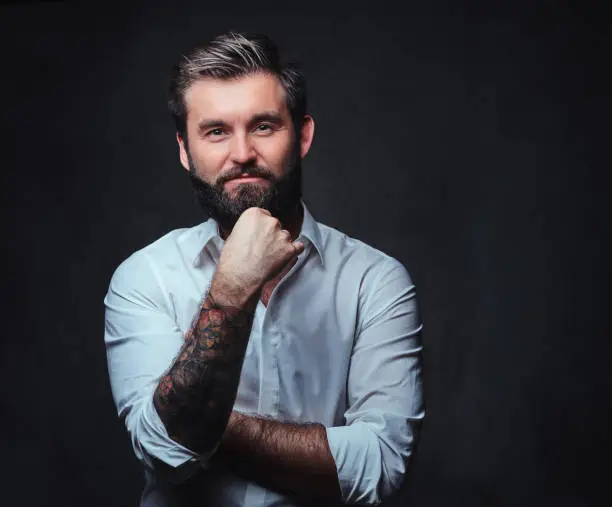 Photo of A man with tattoo on arm dressed in a shirt.