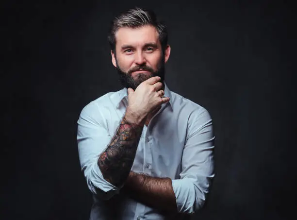Photo of A man with tattoo on arm dressed in a shirt.