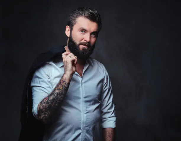 Photo of A man with tattoo on arm dressed in a shirt.