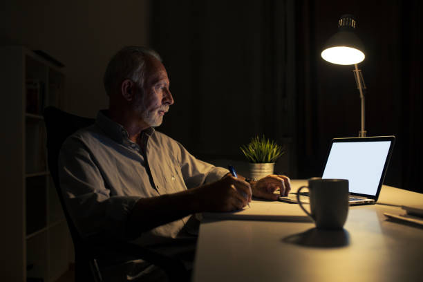 밤에 그의 집에 사무실에서 일 하는 노인 남자의 촬영 스톡 사진