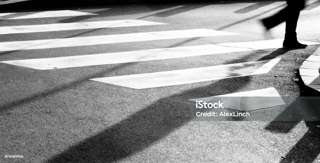 Blurry zebra crossing with person silhouette and shadow Blurry zebra crossing with silhouette and shadow of person walking in the cold and sunny early morning autumn day in black and white Abstract Stock Photo