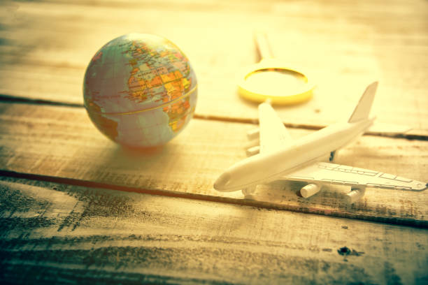 istock Mini airplane and Globe and Magnify Glasses on wooden table texture background. World map travel and Vacation around the world concept 874485698