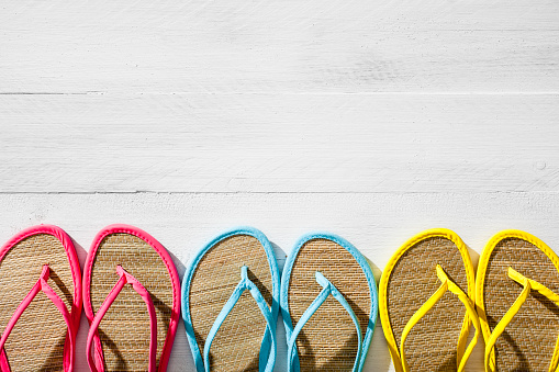 Multi colored flip flops on white wood background