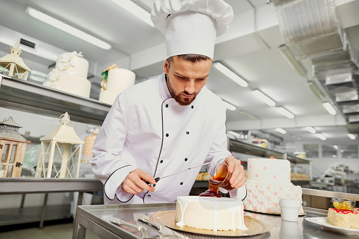 A confectioner with a cake in the bakery.