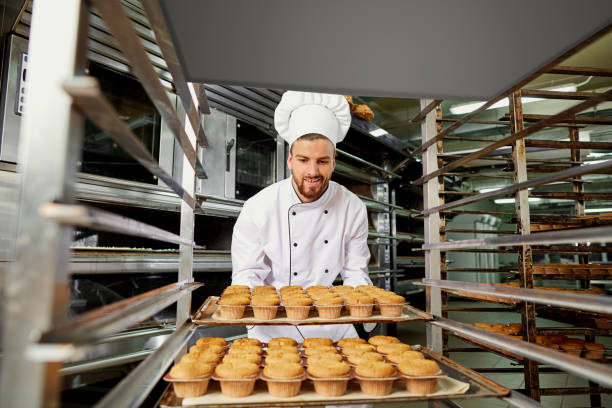 istock A man baker with a tray of cupcakes. 874493060