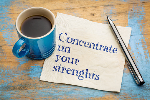 Concentrate on your strenghts - handwriting on a napkin with a cup of espresso coffee
