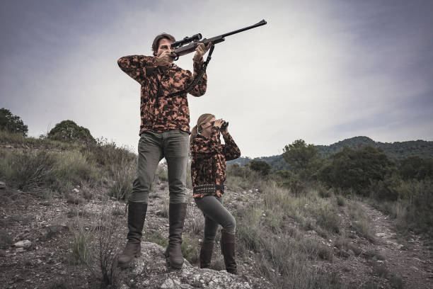 cacciatori uomo con fucile e donna con binocolo in spagna - rifle hunting gun aiming foto e immagini stock