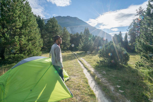 istock Young man relaxing beside tent at sunset, Switzerland 874497714