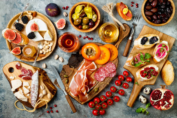 istock Appetizers table with italian antipasti snacks and wine in glasses. Brushetta or authentic traditional spanish tapas set, cheese variety board over grey concrete background. Top view, flat lay 874498532