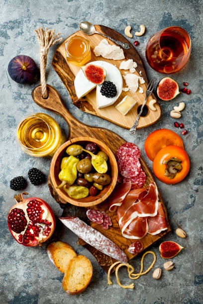 Appetizers table with italian antipasti snacks and wine in glasses. Charcuterie and cheese board over grey concrete background. Top view, flat lay Appetizers table with italian antipasti snacks and wine in glasses. Charcuterie and cheese board over grey concrete background. Top view, flat lay pomegranate in spanish stock pictures, royalty-free photos & images