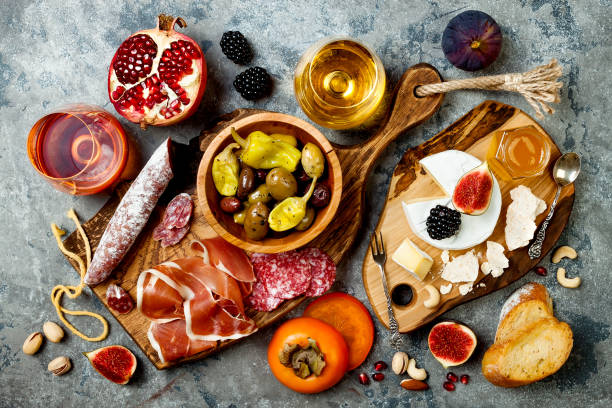 istock Appetizers table with italian antipasti snacks and wine in glasses. Brushetta or authentic traditional spanish tapas set, cheese variety board over grey concrete background. Top view, flat lay 874498656