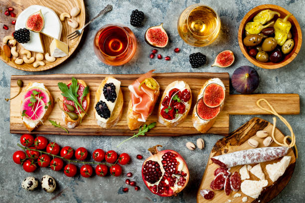 istock Appetizers table with italian antipasti snacks and wine in glasses. Brushetta or authentic traditional spanish tapas set, cheese variety board over grey concrete background. Top view, flat lay 874501342