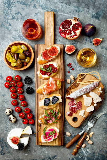 table d’amuse-gueules avec collations antipasti italiens et du vin dans des verres. brushetta ou tapas espagnoles traditionnelles authentiques définie, planches de variété de fromages sur fond de béton gris. vue de dessus, plat lapointe - multi colored picnic dinner lunch photos et images de collection