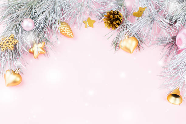 istock Christmas frame with fir branches, conifer cones and ornaments on pastel pink background with snow falling 874514730