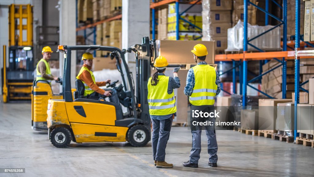 Manual workers working in warehouse Male and female worker working in warehouse. Warehouse Stock Photo