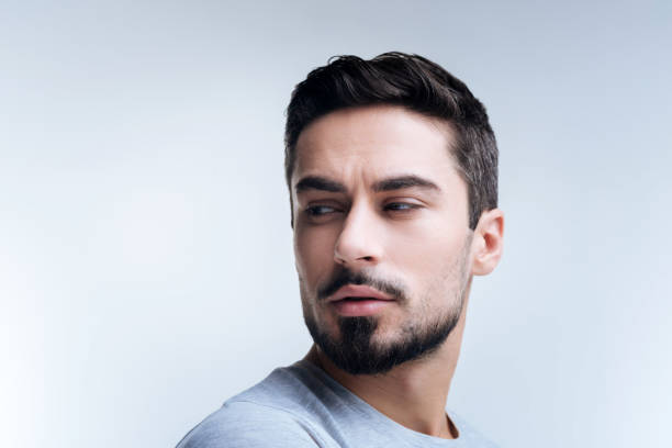 istock Curious young man narrowing his eyes while looking to the right 874537772