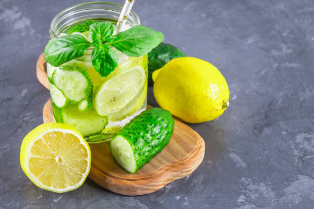 istock Sassy diet water. Cucumber, lemon, mint lemonade in glasses on grey background. 874537824