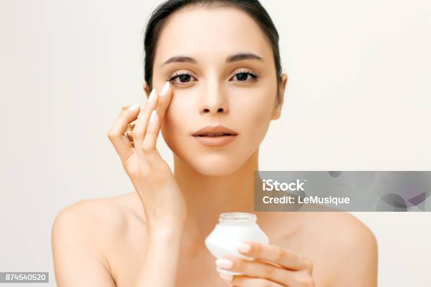 Photo libre de droit de Portrait De La Beauté Naturelle De La Jeune Femme Appliquer La Crème Sur Son Visage banque d'images et plus d'images libres de droit de Oeil