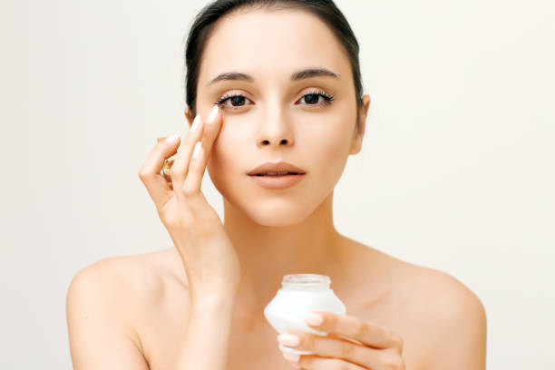 Natural beauty portrait of young woman applying cream on her face stock photo