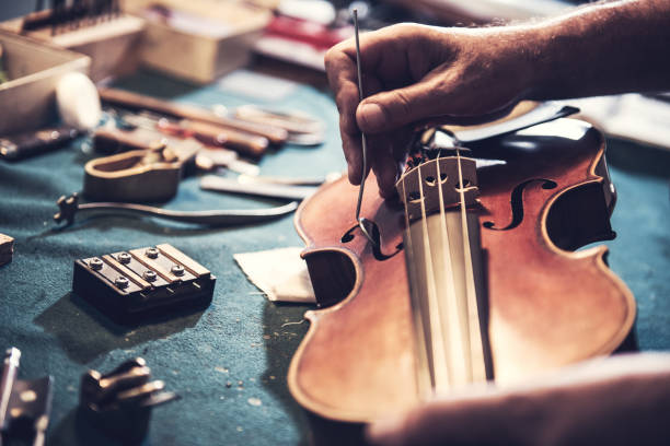 istock Old school repairman looking into violin's soul 874556106