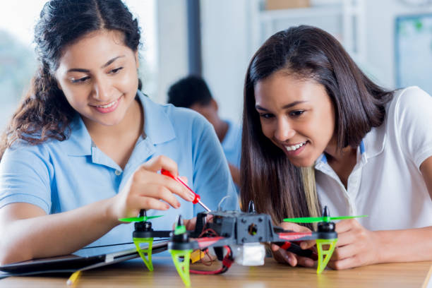 istock Confident teenage girls build drone during science class 874565222