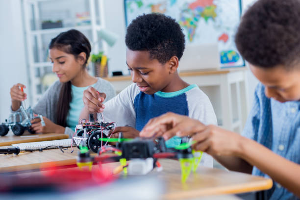 Group of middle school students work on robotics project Happy middle school students work on projects during after school robotics club. They are building robotic vehicles and drones. stem topic stock pictures, royalty-free photos & images