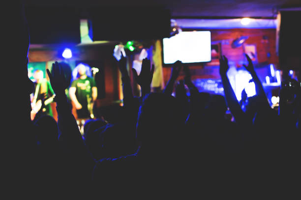 The audience applauds the stage artist in a small club. The audience is in the dark.