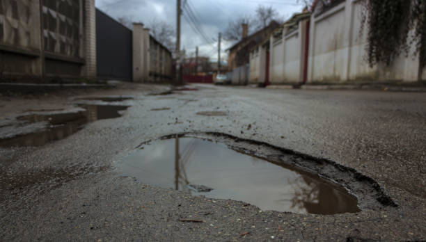 istock Waterfilled pothole on asphalted road 874570226