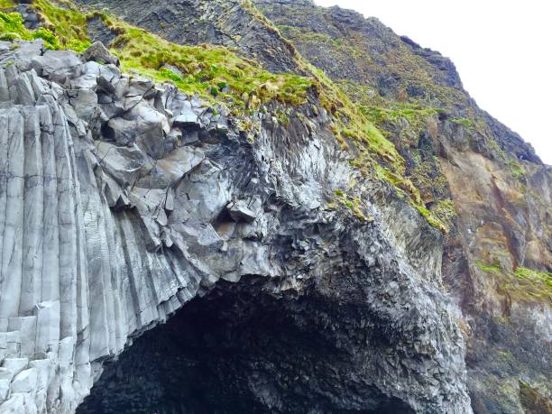 istock Stone cave wit organ pipe looking rocks at Black beach in Iceland 874576230