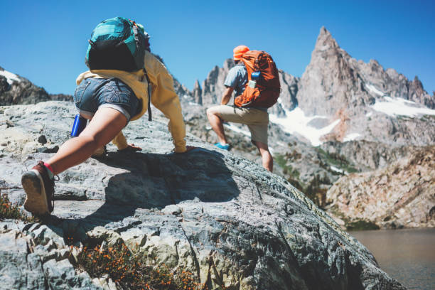 istock Young active couple with backpacks climbing rocks together 874579206