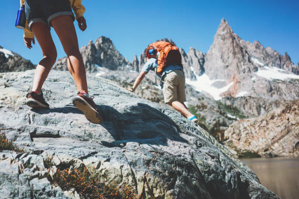 istock Young active couple with backpacks climbing rocks together 874579208