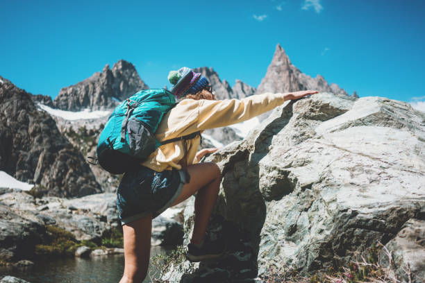 istock Woman backpacker climbing a rock at stunning mountain landscape 874579904