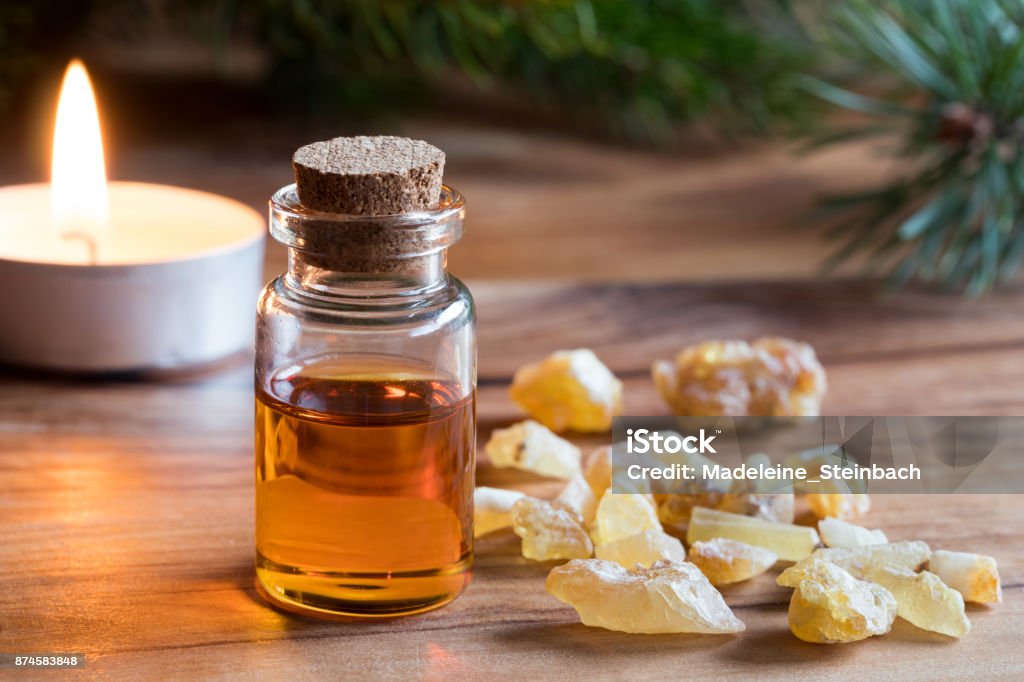 A bottle of frankincense essential oil with frankincense resin A bottle of frankincense essential oil with frankincense resin and a candle in the background Frankincense Stock Photo