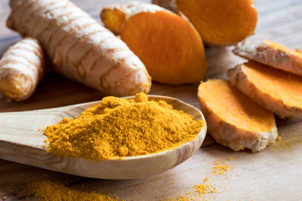 istock Turmeric powder on a wooden spoon, with fresh turmeric root 874588000