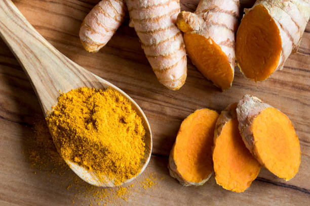 istock Turmeric powder on a wooden spoon, with fresh turmeric root 874588010