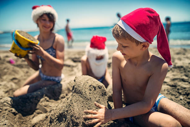 istock Children having fun building christmas sandcastle on beach 874592586