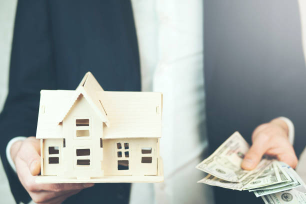 istock business man hand house model with money 874600154