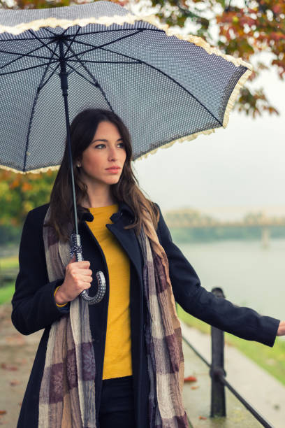 istock Woman with umbrella walking on cloudy autumn day 874603572