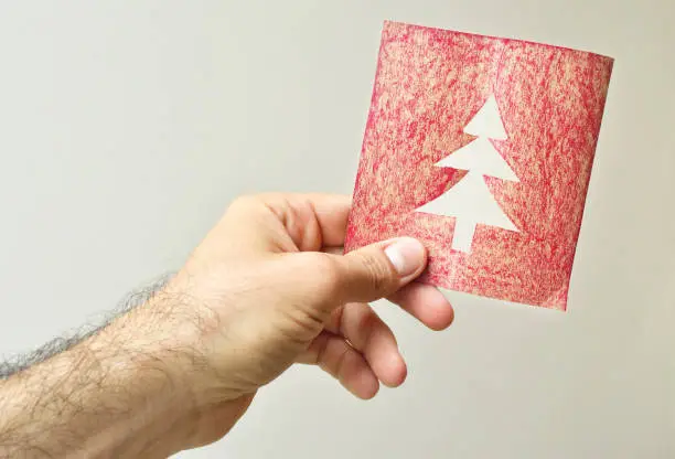 Man's hand holding a Christmas card with a hollow treeMan's hand holding a Christmas card with a hollow tree