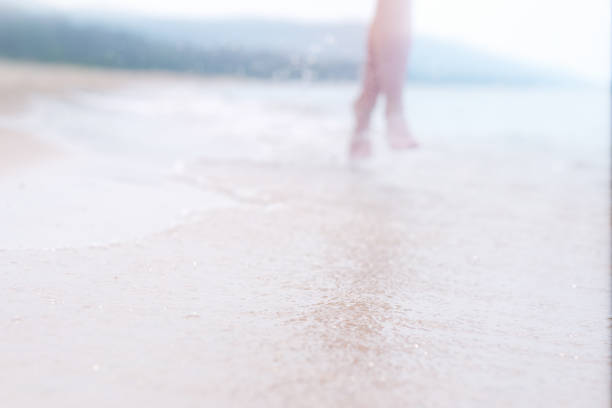 Girl running on beach, girls feet are blurred and out of focus, the sun's rays accentuate the figure