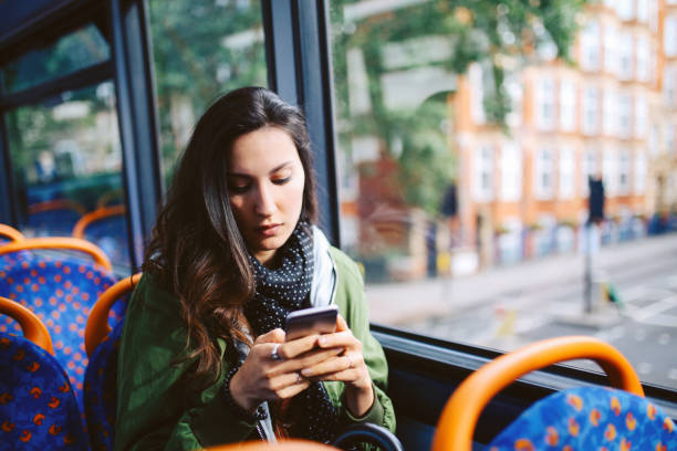 istock Young woman texting while riding on the bus in London 874619408