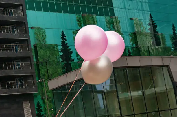 Colorful balloons against glass-facade building.