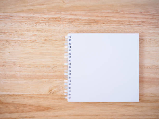 istock white cover notebook on brown wood desk background 874632816