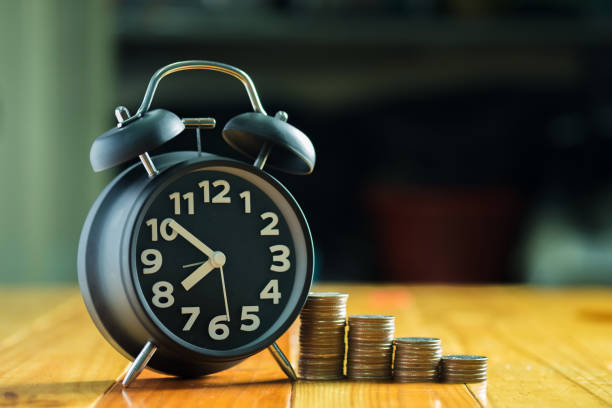 istock Alarm clock and step of coins stacks on working table, time for savings money concept. 874633440