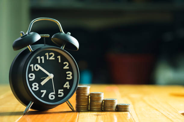 istock Alarm clock and step of coins stacks on working table, time for savings money concept. 874633464