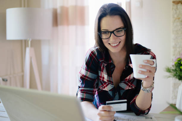 istock Woman having coffee and purchasing online in her home 874652994